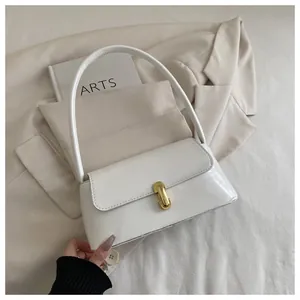 Detailed close-up of white leather shoulder bag with minimalist golden U-shaped buckle