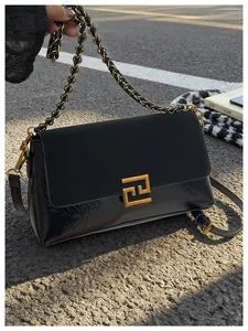 Detail der schwarzen Leder- und Wildledertasche mit Goldbuckle und Kettenträger auf Straße