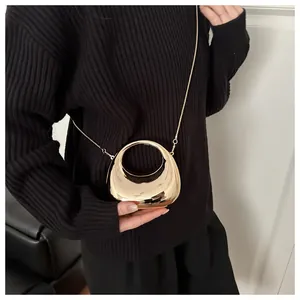 Détail du sac de soirée croissant doré avec finition miroir brillante et bandoulière