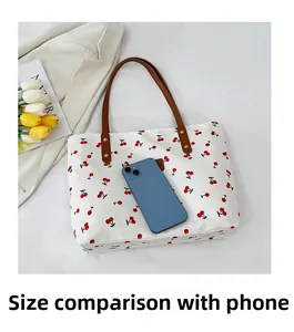 Borsa tote bianca con stampa a ciliegie accanto a smartphone per confronto dimensioni
