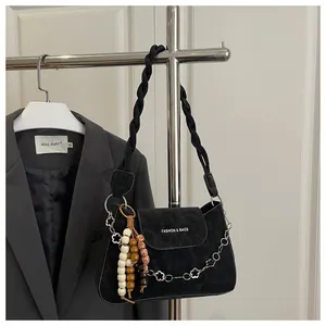 Détail d'un sac à bandoulière noir mat avec sangle tressée et chaîne à fleurs argentée