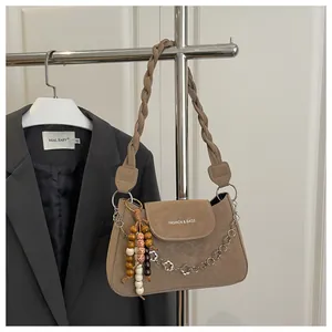 Détail du sac bandoulière mat kaki avec bandoulière tissée et chaîne décorative