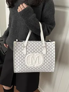 Chic white tote bag with black monogram print and top handles for a modern look