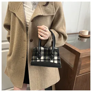 Plaid wool handbag with black leather trim worn by model in autumn street style