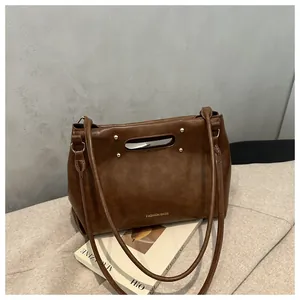 Close-up of vintage brown shoulder bag with golden rivets resting on magazine