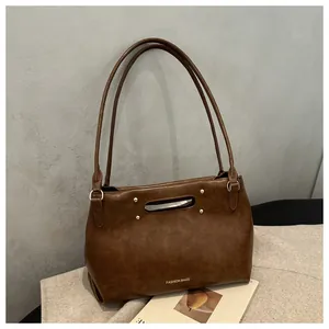 Close-up of vintage brown leather handbag with gold rivets and debossed logo