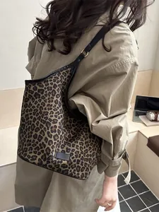 Grand sac cabas léopard avec anses noires porté par un mannequin en trench-coat