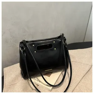 Detail of black faux leather handbag with gold rivets and engraved FASHION BAGS text