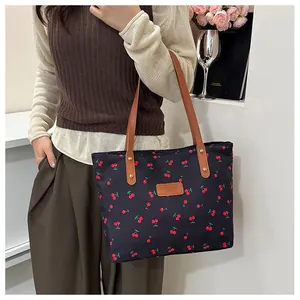 Borsa tote con stampa a ciliegie e manici in pelle indossata da una modella elegante