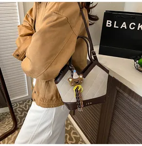 Detail der gesteppten weißen Tasche mit braunem Leder und niedlichem Bären-Anhänger