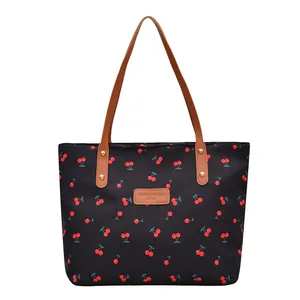 Fashionable black tote bag with cherry print pattern and brown leather handles
