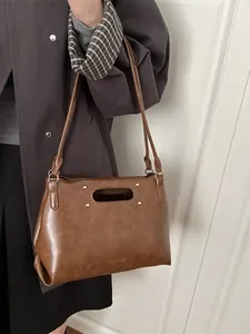 Retro brown faux leather handbag with oval cutout handle and gold stud accents
