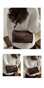 Détail du sac cylindre marron brillant avec emblème doré et bandoulière réglable