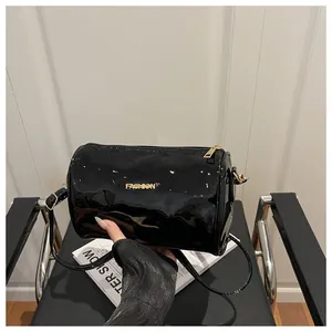 Détail du sac cylindrique noir brillant avec lettrage Fashion en métal doré