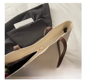 Detailansicht des goldenen Reißverschlusses und der braunen Ledergriffe am Shopper