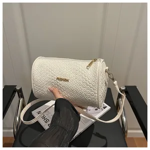 Détail du sac cylindre blanc avec texture tissée et logo fashion doré chic