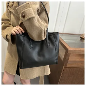 Detailed view of the large black faux leather tote bag worn as a shoulder bag on a model