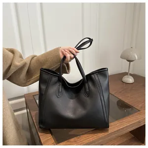 Macro detail of high-quality black leather tote bag on wooden table with warm lighting