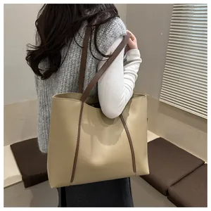 Modell trägt eine große beige Tragetasche mit braunen Griffen im modernen Design