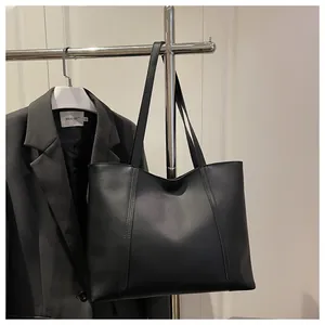 Detail einer schwarzen matten Leder-Tragetasche mit vertikalen Nähten auf grauem Sakko