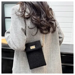 Detail of black plush crossbody bag with gold metal chain strap on grey wool coat