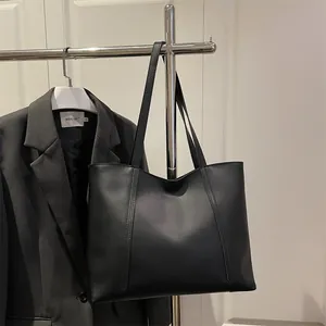 Minimalistische schwarze matte Leder-Tragetasche mit Vertikalnähten und schmalen Riemen