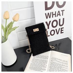 Detail of black plush crossbody bag featuring a golden metal chain and twist-lock clasp