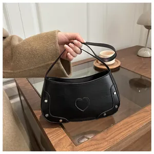 Détail de la texture crocodile noire et des clous argentés sur le sac en forme de coeur