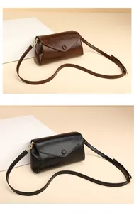 Detail van gladde leren crossbodytassen in donkerbruin en zwart met gouden gespen