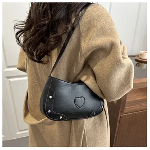 Vue latérale du sac porté épaule en similicuir noir avec patch cœur et clous sur modèle