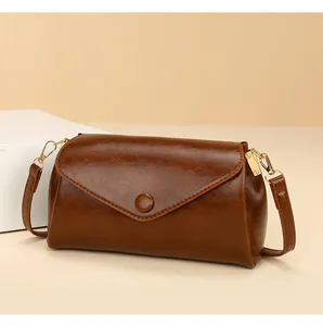 Detail van vintage donkerbruine crossbodytas met olie-was lederen textuur en gouden details