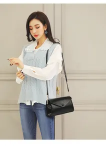 Detail van een zwarte rechthoekige crossbodytas met envelopklep en ronde decoratieve gesp