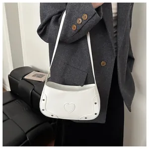 Détail du sac blanc à motif crocodile avec rivets argentés et ornement en forme de cœur
