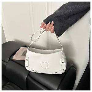 Détail d'un sac blanc à motif crocodile avec un motif cœur brodé et des rivets argentés