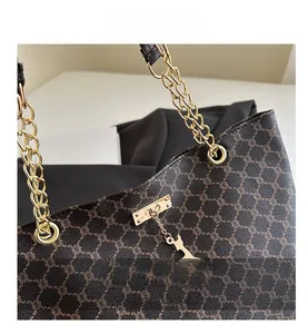 Close-up of retro brown monogram tote with gold chain strap and giraffe pendant