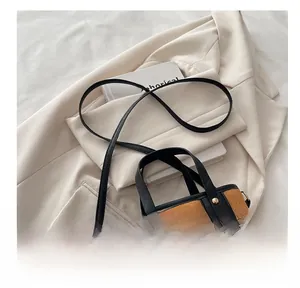 Detail of caramel quilted bucket bag with golden rivets and contrasting black handle straps