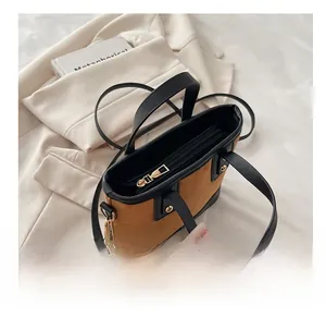 Detail of smooth golden zipper and black leather trim on brown suede bucket bag