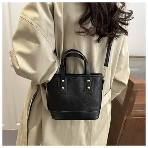Detail of black quilted bucket bag featuring gold stud accents and detachable strap