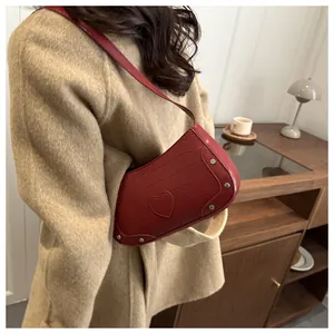 Détail du sac bandoulière rouge à motif crocodile avec cœur et rivets argentés