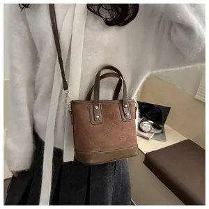 Detail of a brown suede mini bucket bag with quilted stitching and gold rivet accents