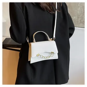 Primer plano de bolso bandolera blanco con cadena dorada sobre una chaqueta negra