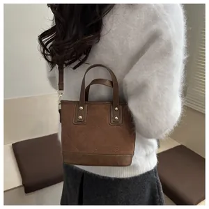 Detail of brown quilted bucket bag featuring gold rivets and detachable crossbody strap