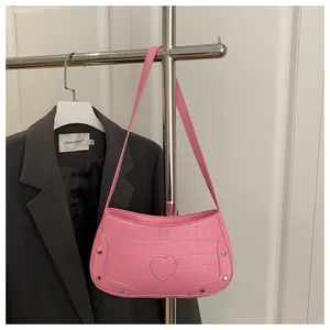 Détail du sac bandoulière rose à texture crocodile et empiècement cuir en forme de cœur