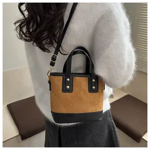 Detail of suede bucket bag with quilted stitching and gold hardware on model