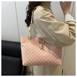 Close-up of pink tote bag with M-pattern print, golden deer charm and chain detail