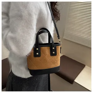 Retro brown corduroy bucket bag with diamond stitching and rivets shown on a model