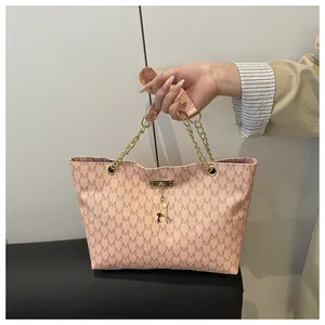 Detail of pink tote bag featuring M-letter print, gold deer charm and chain handle