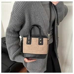 Detail of khaki quilted bucket bag with gold studs and black leather trim worn by a model