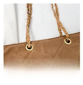 Detail of the golden metal buckle and chain strap on the brown quilted suede shoulder bag