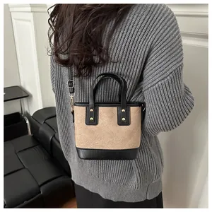 Detailed back view of a woman wearing a black and khaki quilted mini bucket crossbody bag